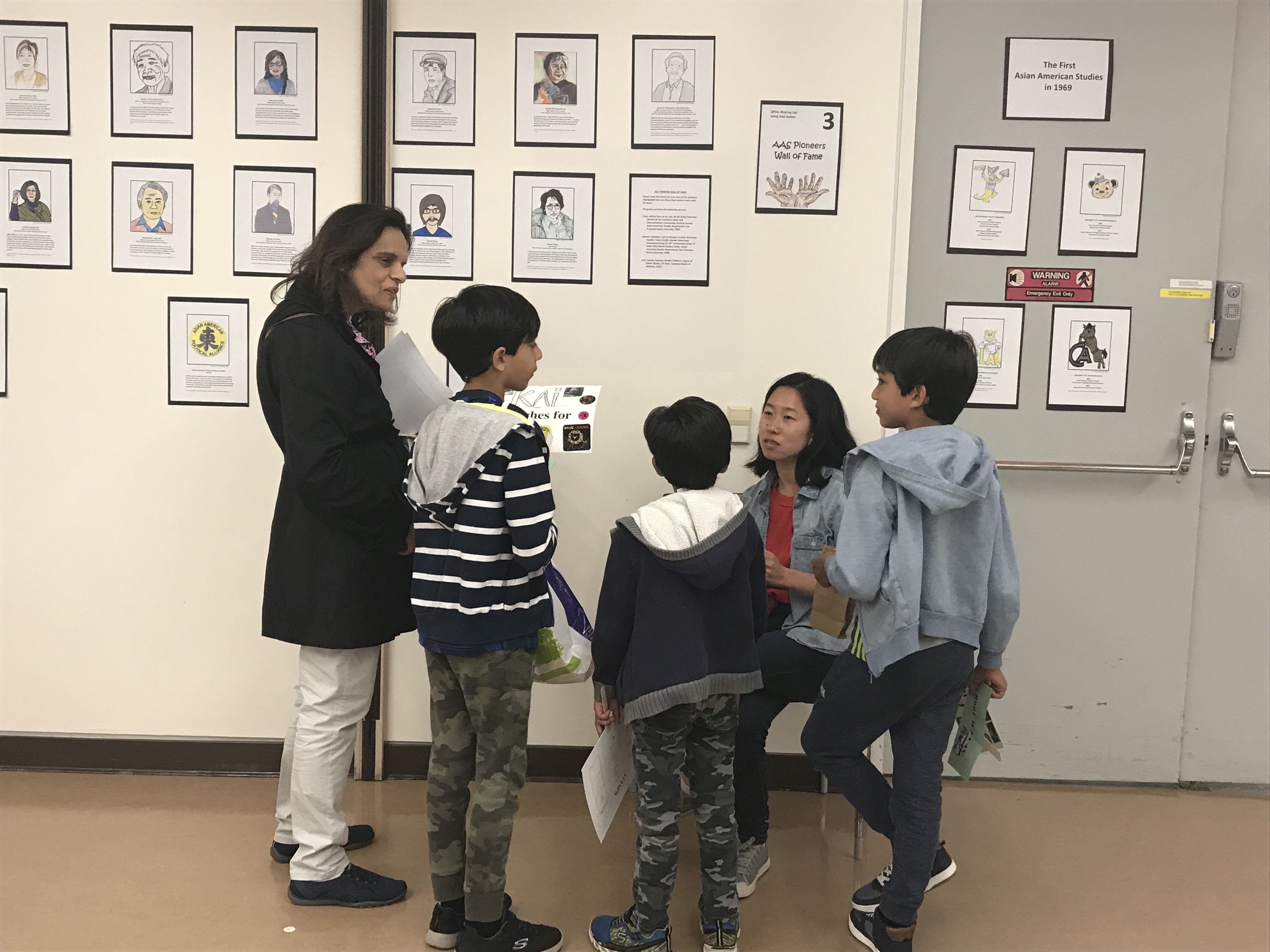 Student explains the Wall of Fame to 3 children as parent watches